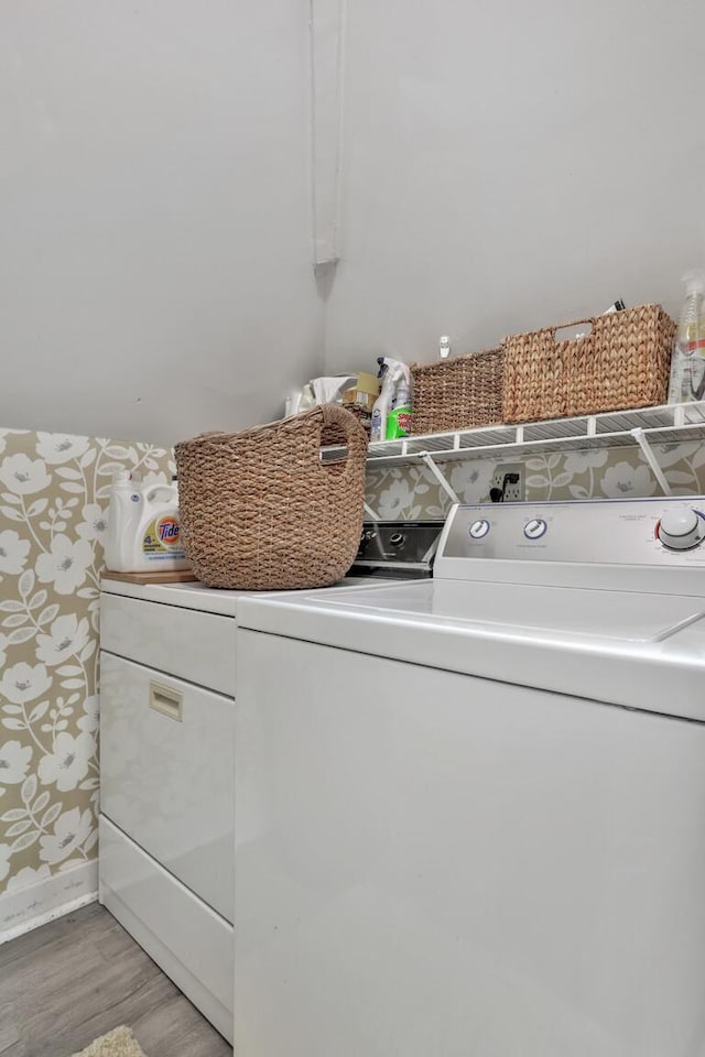 clothes washing area with washing machine and clothes dryer and light wood-type flooring