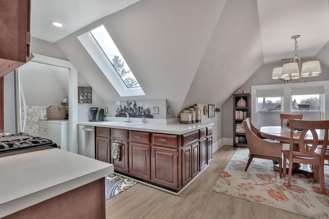 kitchen featuring sink, light wood-type flooring, hanging light fixtures, and vaulted ceiling with skylight