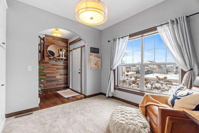 interior space featuring baseboards, carpet, visible vents, and arched walkways