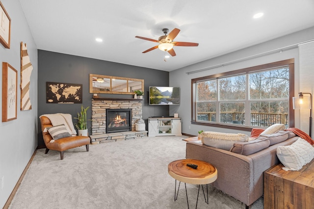 living area featuring baseboards, carpet, a stone fireplace, recessed lighting, and a ceiling fan