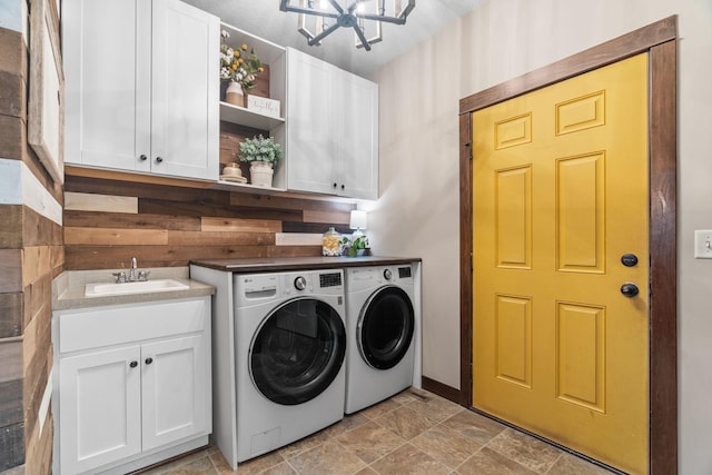 washroom with a sink, cabinet space, washing machine and dryer, and stone finish floor