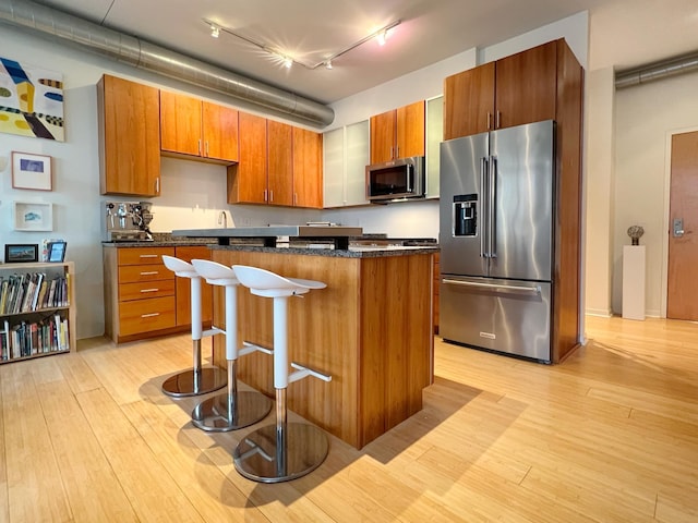 kitchen with a center island, rail lighting, light hardwood / wood-style flooring, a kitchen bar, and appliances with stainless steel finishes