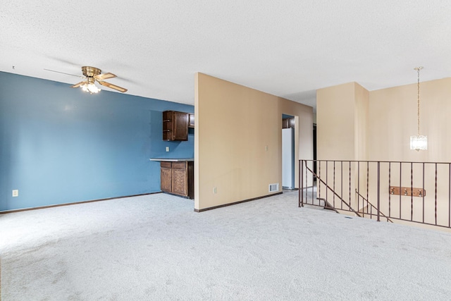 carpeted spare room with a textured ceiling and ceiling fan with notable chandelier