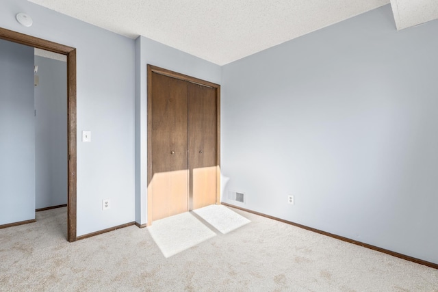 unfurnished bedroom featuring a closet, light carpet, and a textured ceiling