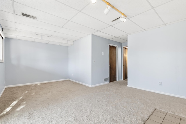 carpeted spare room featuring a drop ceiling