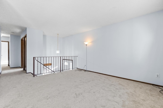 spare room with light colored carpet and a textured ceiling