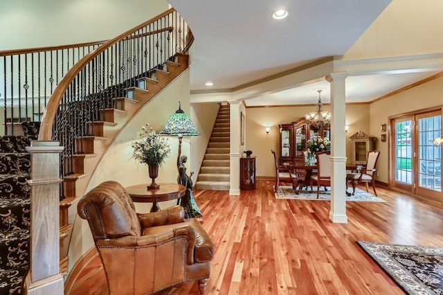 interior space with decorative columns, wood-type flooring, crown molding, and an inviting chandelier