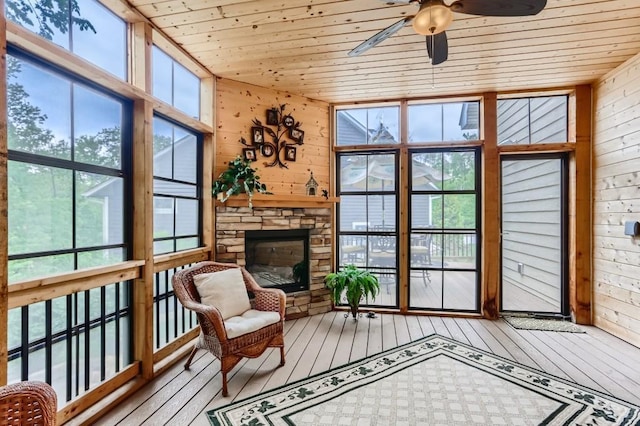 sunroom / solarium with a stone fireplace, a wealth of natural light, and wood ceiling