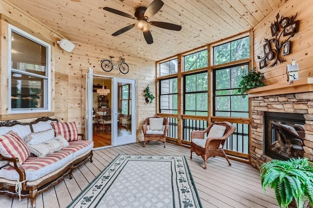 sunroom featuring ceiling fan, a fireplace, wooden ceiling, and vaulted ceiling