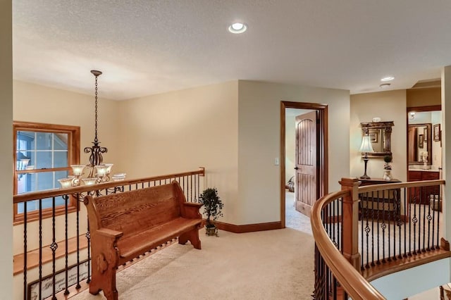 living area featuring light carpet, a textured ceiling, and a notable chandelier