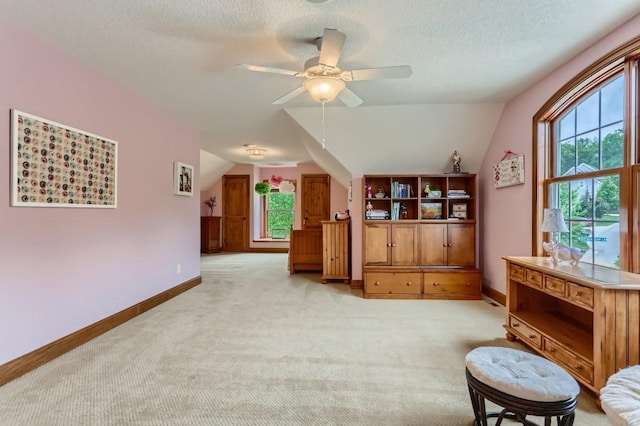 living area with a textured ceiling, light carpet, ceiling fan, and lofted ceiling