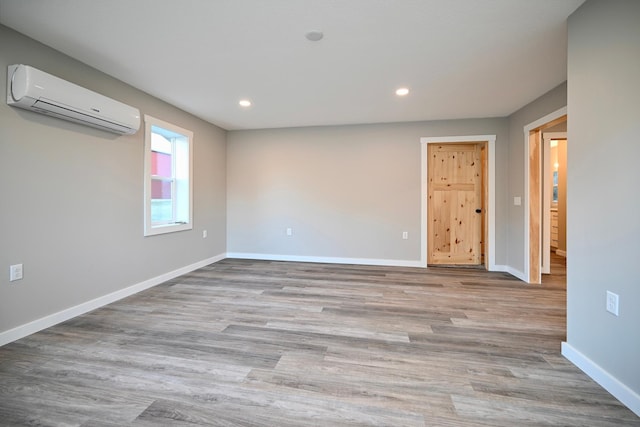 spare room featuring light wood-type flooring and a wall unit AC