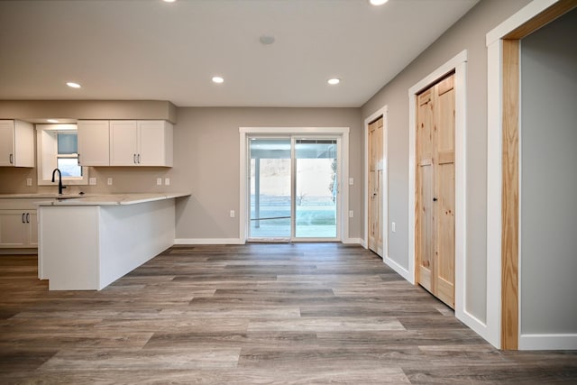 kitchen with kitchen peninsula, white cabinets, and hardwood / wood-style flooring