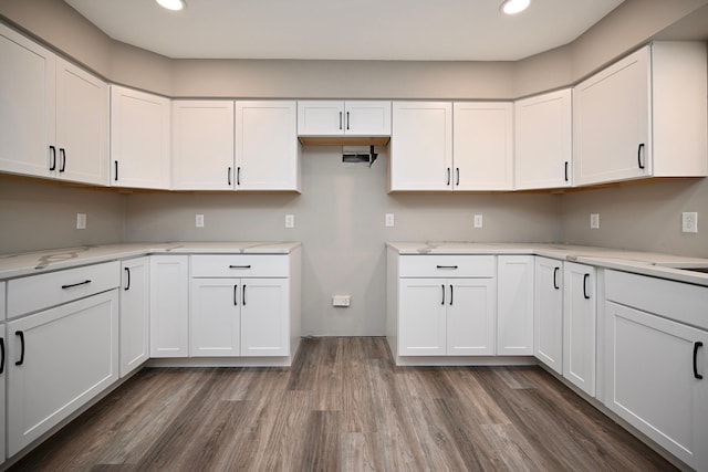 kitchen featuring white cabinets, light stone counters, and dark wood-type flooring