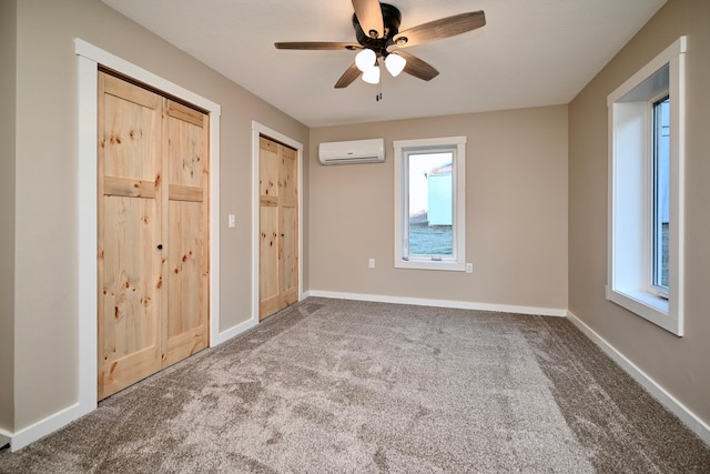 unfurnished bedroom featuring two closets, a wall unit AC, multiple windows, and ceiling fan