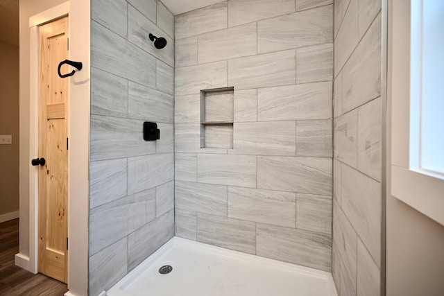 bathroom featuring wood-type flooring and tiled shower