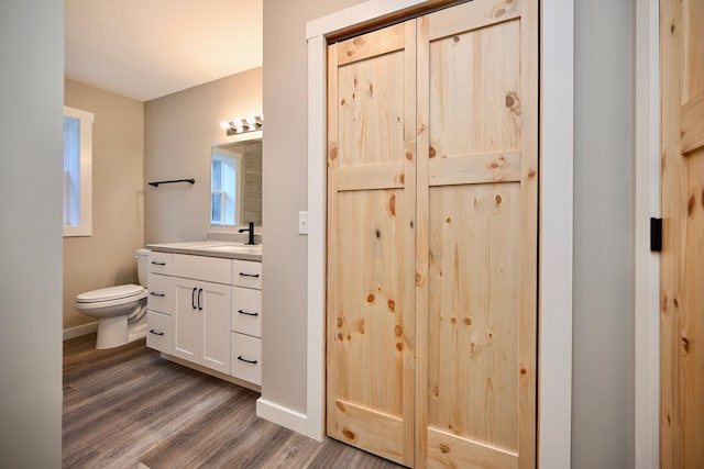 bathroom with wood-type flooring, vanity, and toilet