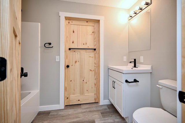 full bathroom with hardwood / wood-style flooring, vanity, toilet, and shower / bathing tub combination