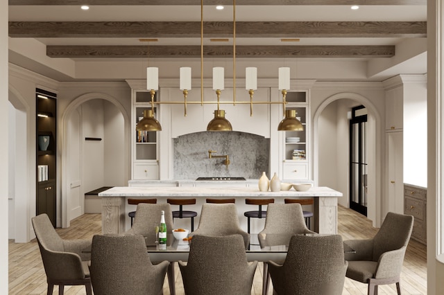 kitchen with beamed ceiling, decorative light fixtures, light hardwood / wood-style floors, and a kitchen breakfast bar