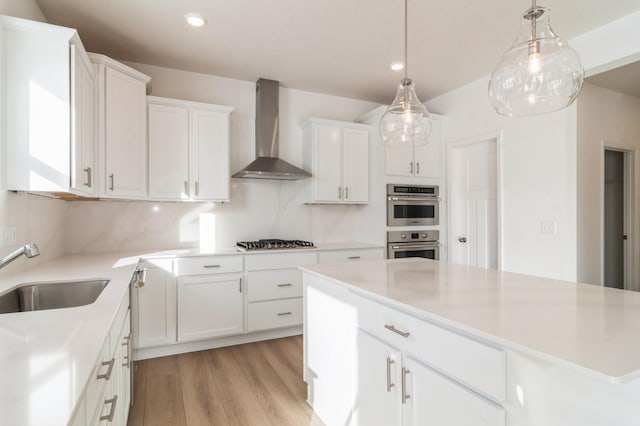 kitchen with white cabinets, sink, wall chimney range hood, and stainless steel appliances