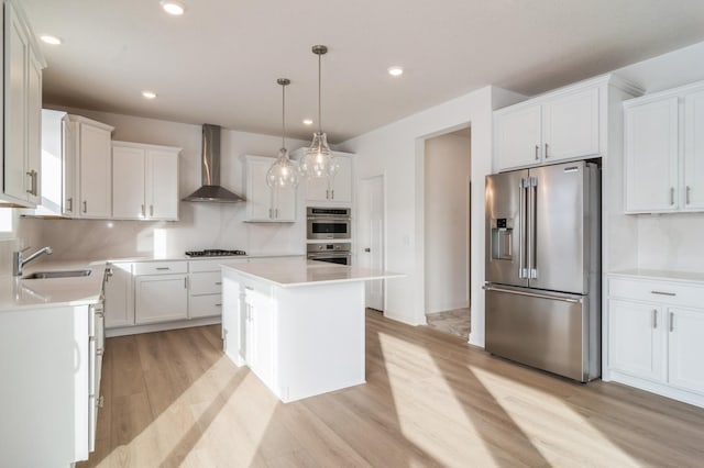 kitchen with white cabinets, a center island, wall chimney exhaust hood, stainless steel appliances, and sink