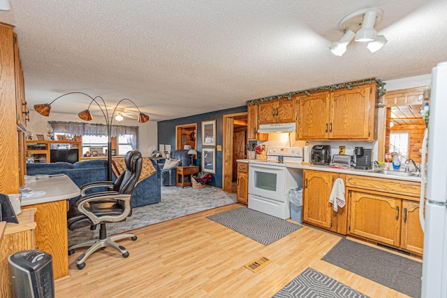 kitchen with a textured ceiling, sink, light hardwood / wood-style floors, and white appliances