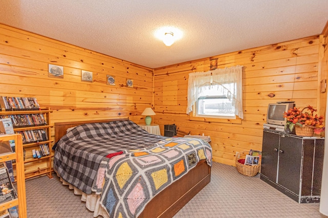 bedroom with a textured ceiling, carpet floors, and wooden walls