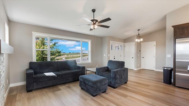 living room featuring ceiling fan with notable chandelier, light hardwood / wood-style floors, and vaulted ceiling