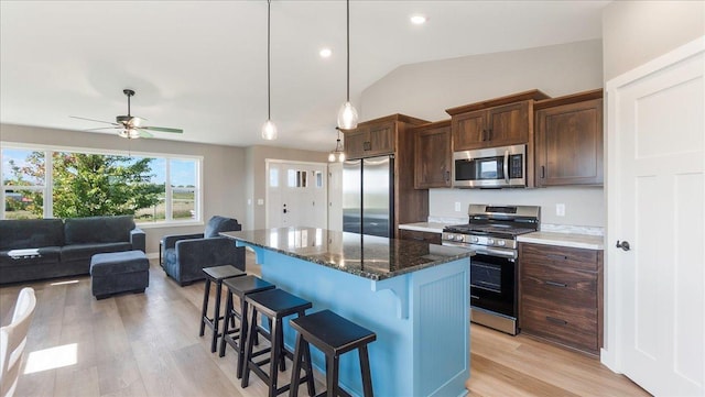 kitchen with a center island, light hardwood / wood-style flooring, dark stone countertops, lofted ceiling, and appliances with stainless steel finishes