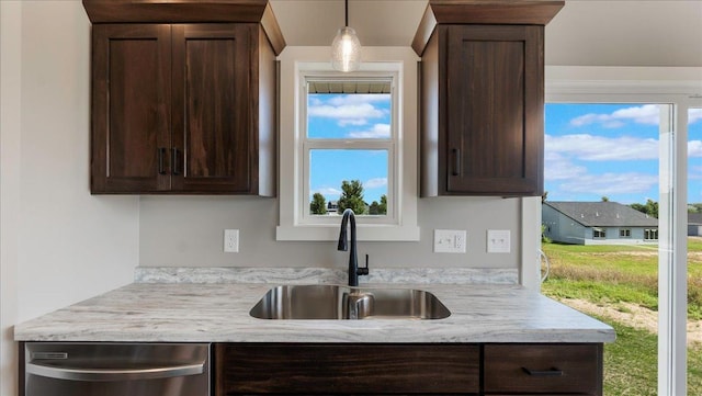 kitchen with pendant lighting, dark brown cabinetry, stainless steel dishwasher, and sink