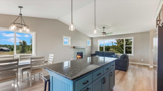 kitchen with ceiling fan with notable chandelier, decorative light fixtures, light hardwood / wood-style flooring, a fireplace, and a center island