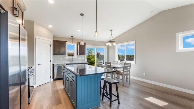 kitchen with pendant lighting, a kitchen island, appliances with stainless steel finishes, and light hardwood / wood-style flooring