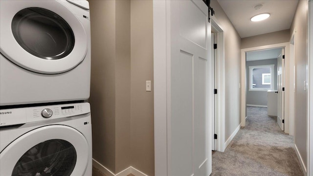 clothes washing area with light carpet, a barn door, and stacked washer / drying machine