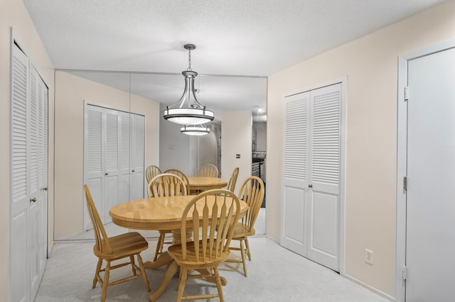 dining area featuring a textured ceiling and light carpet