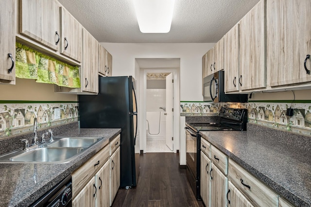 kitchen featuring black appliances, sink, light brown cabinetry, and washing machine and clothes dryer