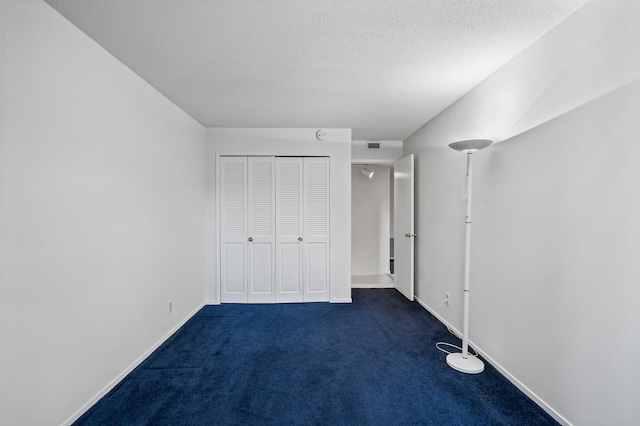 unfurnished bedroom with a closet, dark carpet, and a textured ceiling