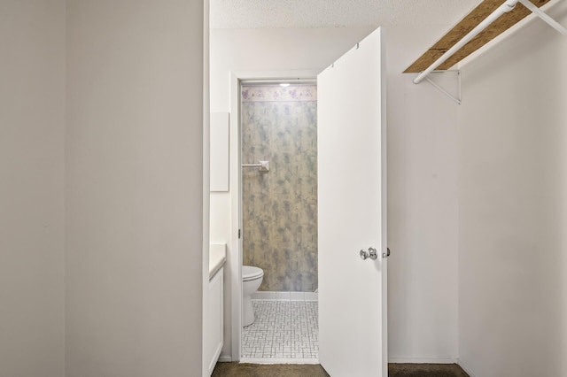 bathroom featuring vanity, a textured ceiling, and toilet