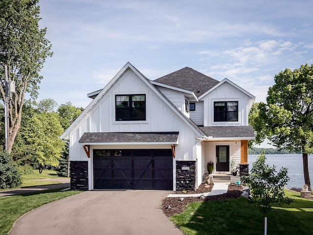 modern inspired farmhouse with a water view, a garage, and a front lawn