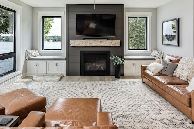 living room with a large fireplace, a healthy amount of sunlight, and light hardwood / wood-style floors