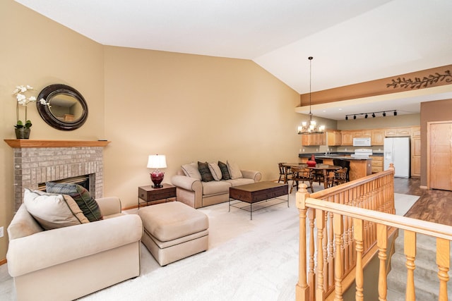 living room featuring carpet floors, vaulted ceiling, a fireplace, and an inviting chandelier