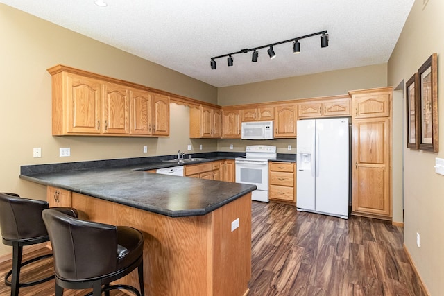 kitchen with dark wood-type flooring, white appliances, kitchen peninsula, and a textured ceiling