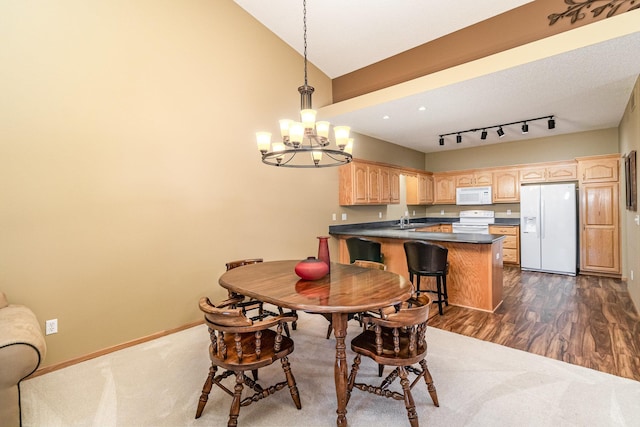 dining area featuring sink, vaulted ceiling, dark hardwood / wood-style flooring, and an inviting chandelier