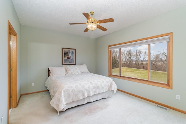 bedroom featuring ceiling fan, a textured ceiling, and light carpet