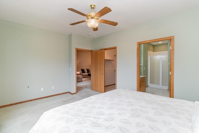 carpeted bedroom with ceiling fan, connected bathroom, a textured ceiling, a walk in closet, and a closet