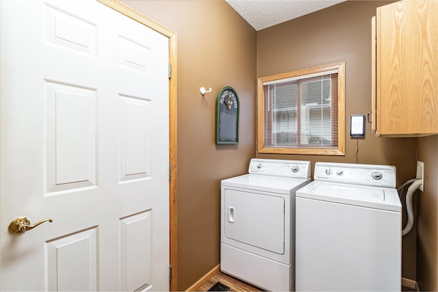 washroom with a textured ceiling, washing machine and clothes dryer, and cabinets