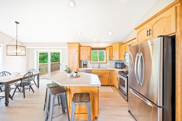 kitchen featuring a chandelier, appliances with stainless steel finishes, light wood-type flooring, a kitchen island, and sink