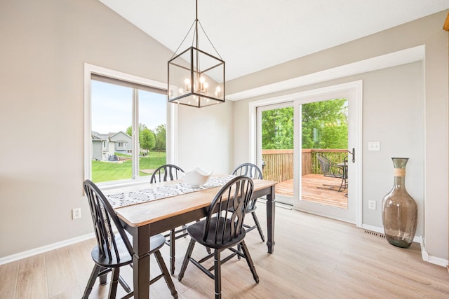 dining room featuring an inviting chandelier, vaulted ceiling, and light hardwood / wood-style flooring