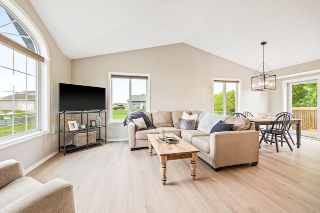 living room with lofted ceiling, an inviting chandelier, and light hardwood / wood-style floors