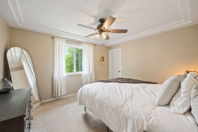 carpeted bedroom with a raised ceiling and ceiling fan