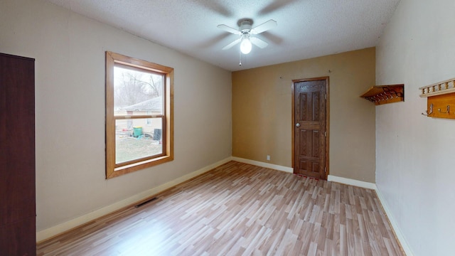 empty room featuring ceiling fan, a textured ceiling, and light wood-type flooring